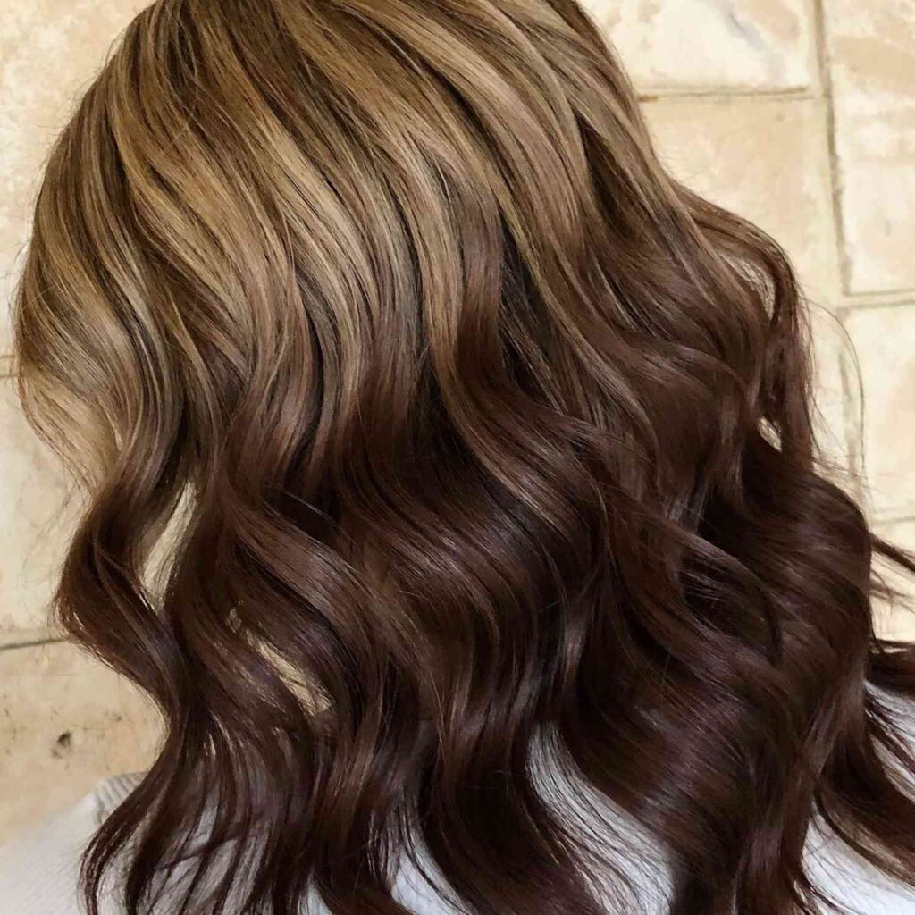 Natural sun-kissed ombre hair with low-contrast gradients from brunette roots to caramel or honey tones — effortless 2025 hair trend.