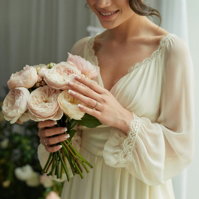 Elegant French tip nails for a wedding on a bride holding bouquet